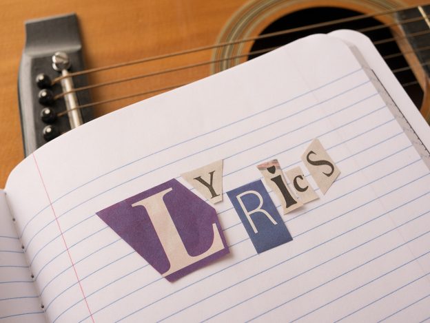 Cut out letters placed on a notebook spell lyrics